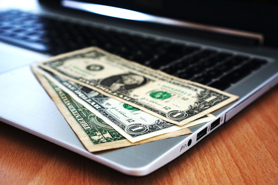 Close-up of US dollar bills placed on a laptop symbolizing digital finance and economy. — Photo by Pixabay